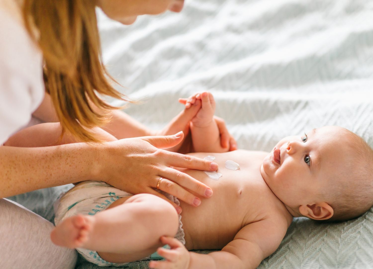 Mutter schmirt Baby mit Hautpfelge ein